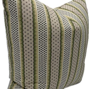 May include: A decorative pillow with a beige background and vertical stripes. The stripes alternate between patterns of small black circles, green floral designs, and tiny star-shaped flowers. The pillow is a square shape.