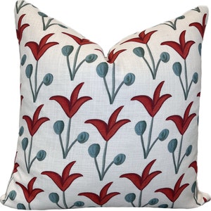 May include: A white cushion with a red and blue floral pattern. The cushion features a repeating pattern of stylised red tulips with blue buds and stems.