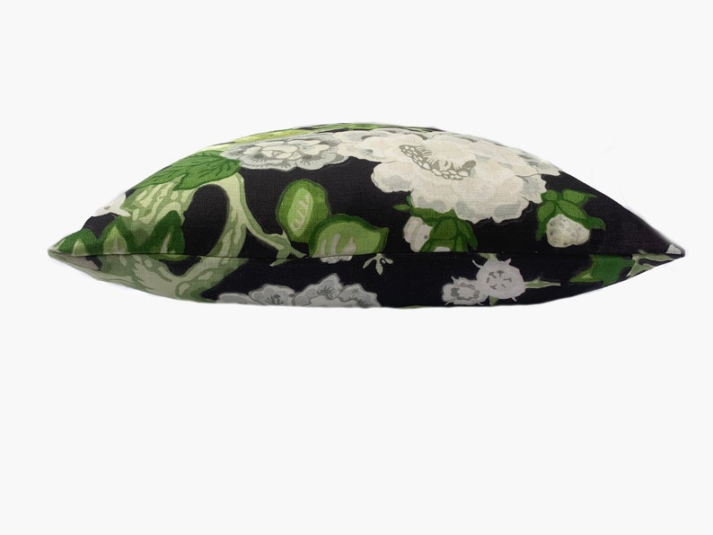 May include: A black pillow with a white and green floral pattern.