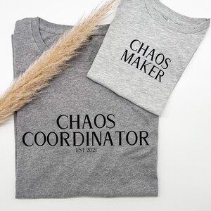 Könnte beinhalten: Zwei graue T-Shirts mit schwarzem Text. Das obere Shirt sagt "Chaos Maker". Das untere Shirt sagt "Chaos Coordinator Est 2021".