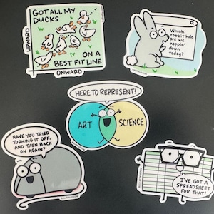 May include: A collection of five humorous stickers with cartoon illustrations. One sticker features ducks on a graph with the text "Got All My Ducks". Other stickers include a rabbit, a mouse, and a spreadsheet with speech bubbles.
