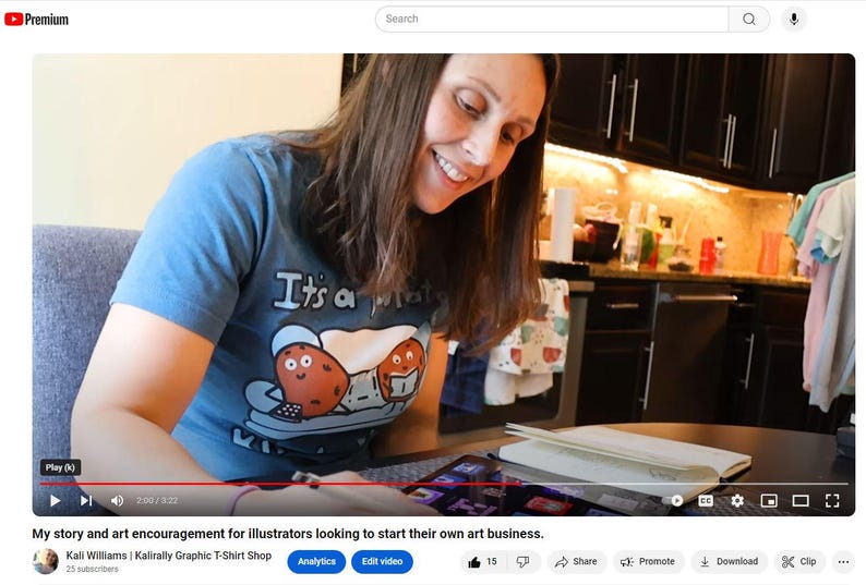 K&ouml;nnte beinhalten: Eine Frau tr&auml;gt ein blaues T-Shirt mit dem Text "It's a potato" und einer Comic-Kartoffelgrafik. Sie sitzt an einem Tisch und arbeitet an einem Laptop. Sie schaut auf den Bildschirm und l&auml;chelt.