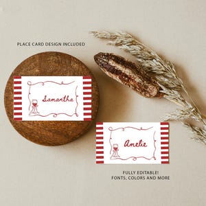May include: Two place cards with red and white striped borders and a wine glass illustration. One card says "Samantha" and the other says "Amelie" in red script. The cards are on a wooden surface. Text on the image says "PLACE CARD DESIGN INCLUDED" and "FULLY EDITABLE! FONTS, COLORS AND MORE".