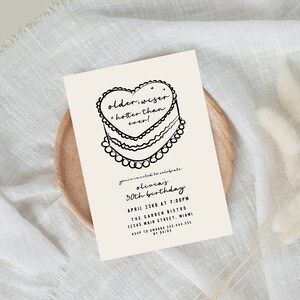 Puede incluir: Una tarjeta de invitaci&oacute;n blanca con texto negro y una ilustraci&oacute;n dibujada a mano de un pastel en forma de coraz&oacute;n. El texto dice "older, wiser, hotter than ever!" y "You're invited to celebrate Olivia's 30th birthday, April 2388 at 7:00PM, The Garden Bistro, 12345 Main Street, Miami, RSVP to 323-444-555 by 28.18."