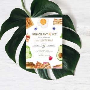 May include: A white invitation card with a watercolour illustration of breakfast foods, including waffles, eggs, bacon, avocado, and fruit. The text on the card reads "BRUNCH ANYONE?" and "Lannes 7th Birthday".
