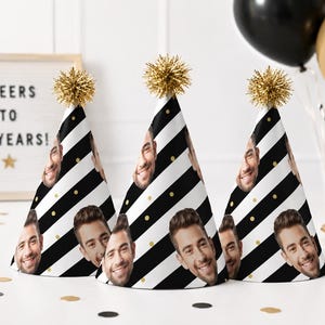 Pode incluir: Três chapéus de festa cónicos com um padrão repetitivo de riscas diagonais pretas e brancas, pequenos pontos dourados e o rosto de uma pessoa sorridente. Cada chapéu é rematado com um pompom de espumilhão dourado metálico.