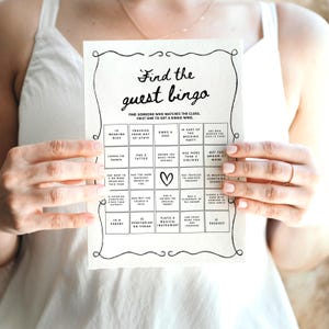 Pu&ograve; includere: Una scheda di bingo per matrimoni stampabile con un design in bianco e nero. La scheda ha un cuore al centro ed &egrave; piena di caselle che contengono indizi per gli ospiti da trovare al matrimonio. Il testo sulla scheda dice "Find the guest bingo".
