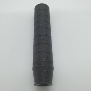 May include: A black rubber grip with a textured surface. The grip is designed to fit on a tool or other object.