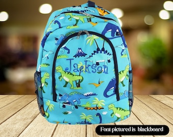 May include: Blue dinosaur backpack with a mesh side pocket and a zippered front pocket. The backpack is personalized with the name "Jackson" in a black font.