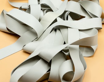 May include: A pile of light gray elastic bands, made in the USA.