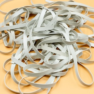 May include: A pile of white rubber bands, made in the USA.