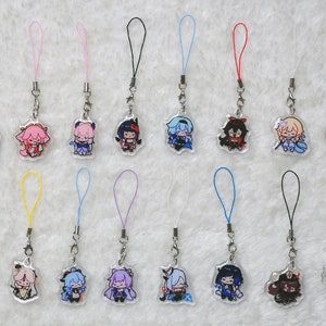 May include: A selection of acrylic charms with anime-style character designs. Each charm showcases a different character, with bright colours and detailed artwork. They are attached to a silver chain with a coloured loop.