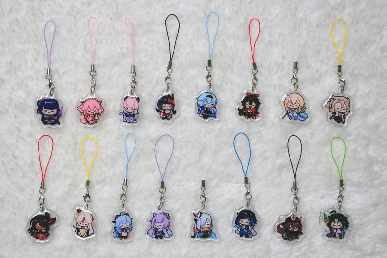 May include: A selection of acrylic charms with anime-style character designs. Each charm showcases a different character, with bright colours and detailed artwork. They are attached to a silver chain with a coloured loop.