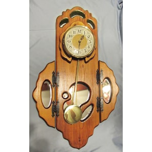 May include: A wooden wall clock with a pendulum and a mirror on each side. The clock face is gold with black Roman numerals and a gold second hand.