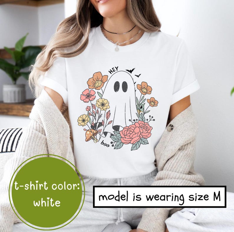 May include: White t-shirt with a ghost and flowers graphic. The text "Hey Boo" is printed on the shirt. The model is wearing size M.