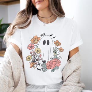 May include: White t-shirt with a graphic of a ghost in a field of flowers. The text "Hey boo" is printed below the ghost.