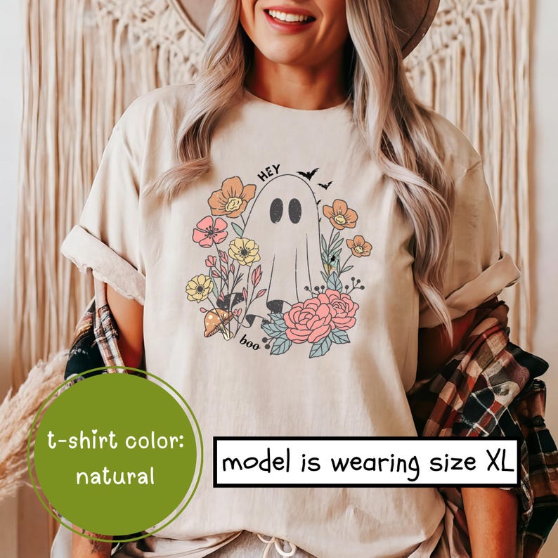 May include: A beige t-shirt with a graphic of a ghost surrounded by flowers. The text "Hey Boo" is printed on the shirt.