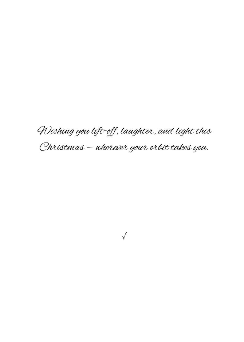 May include: A white card with elegant cursive text. The text reads: "Wishing you lift-off, laughter, and light this Christmas - wherever your orbit takes you." A small checkmark is at the bottom.