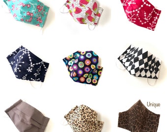 May include: Nine different face masks with various patterns and colors. The masks are made of fabric and have elastic ear loops. The masks are all folded and laid out on a white surface. The text "Unique Super FIT Design" is visible in the bottom right corner of the image.