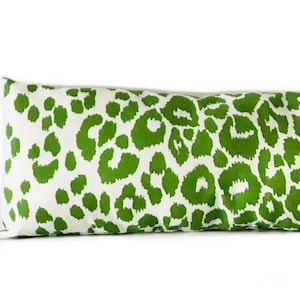Puede incluir: Una almohada larga y rectangular con fondo blanco y estampado de leopardo verde.