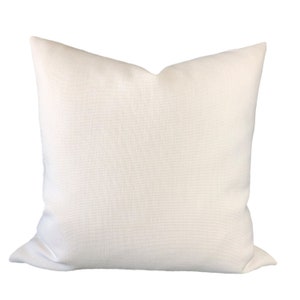 May include: A white, square pillow with a textured fabric. The pillow is made of a soft, comfortable material and is perfect for adding a touch of elegance to any room.