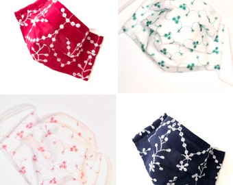 May include: Four face masks in different colors: red with white embroidery, white with green embroidery, white with pink embroidery, and navy blue with white embroidery. Each mask has a floral design and white elastic ear loops.