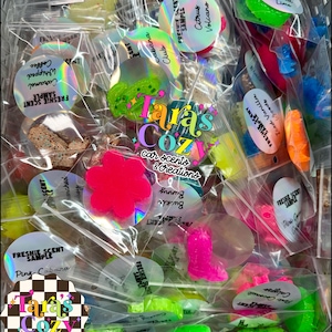 May include: A clear bag filled with colorful car air fresheners in various shapes, including flowers, boots, and geometric designs. The air fresheners are in shades of pink, green, orange, and blue. Each freshener is labeled with a scent name.