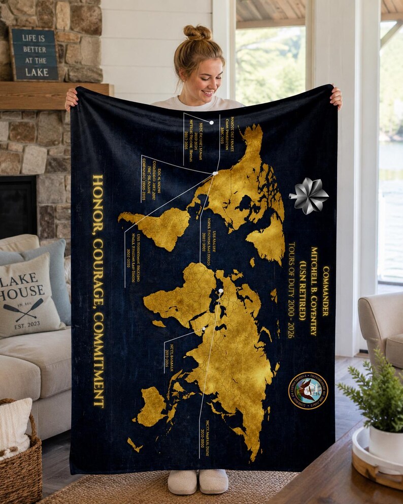 May include: A navy blue blanket with a gold world map design. The blanket features text that reads "Honor, Courage, Commitment" and "Commander Mitchell B. Coventry (USN Retired)". The blanket is held up by a person.