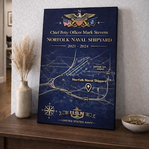 May include: A navy blue canvas print featuring a map of Norfolk Naval Shipyard, with text including "Chief Petty Officer Mark Stevens" and "2021-2024." The U.S. Navy emblem is at the bottom. The print is displayed on a wooden table.