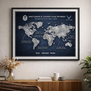 May include: A framed wall print featuring a metallic silver world map on a dark blue textured background. It displays the text MSGT JASON K. LIANDO (USAF RETIRED), TOURS OF DUTY 2001-2018, and FLY-FIGHT-WIN, with lines pointing to specific global locations.