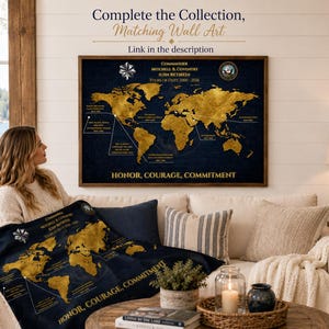 May include: A navy blue world map with gold continents and text, including "Commander Mitchell & Coventry" and "Honor, Courage, Commitment." The map is displayed on a wall and on a blanket. The image also includes a sofa, pillows, and a coffee table.