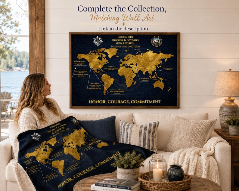 May include: A navy blue world map with gold continents and text, including "Commander Mitchell & Coventry" and "Honor, Courage, Commitment." The map is displayed on a wall and on a blanket. The image also includes a sofa, pillows, and a coffee table.