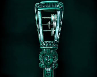 May include: A green musical instrument with a carved female face and a series of metal discs that make a sound when shaken.