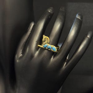 Może przedstawiać: Złoty pierścionek z niebieskim turkusem w kształcie kota.