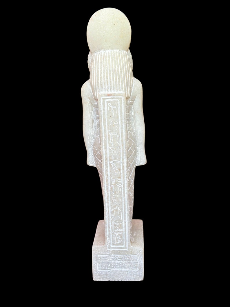 May include: White stone statue of an Egyptian god with hieroglyphics on the front. The statue is standing on a square base.