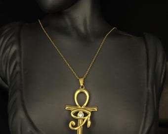 Op de afbeelding: Een gouden ketting met een gouden ankh-hanger met een helder kristal oog van Horus. De ankh is een symbool van eeuwig leven in de oude Egyptische cultuur.