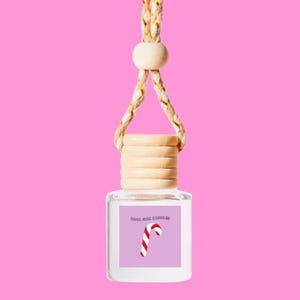 May include: A clear glass bottle with a wooden cap and a string for hanging. The bottle has a label that says "Cool Girl Candles" and a red and white candy cane graphic.
