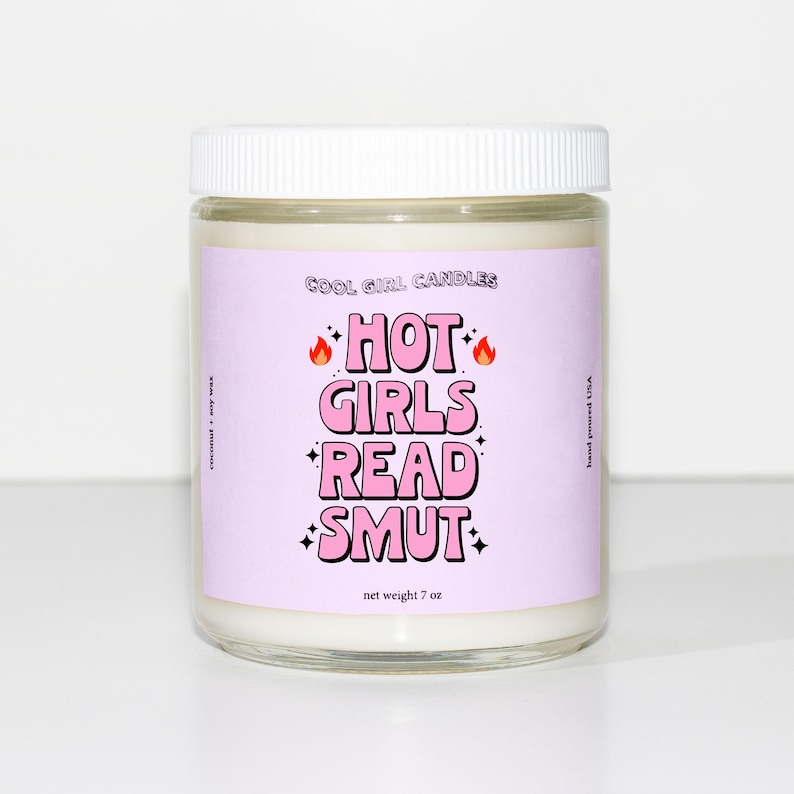 K&ouml;nnte beinhalten: Ein violettes Kerzengef&auml;&szlig; mit einem wei&szlig;en Deckel und einem rosa Etikett, auf dem "Cool Girl Candles" und "Hot Girls Read Smut" steht. Die Kerze ist 7 oz.