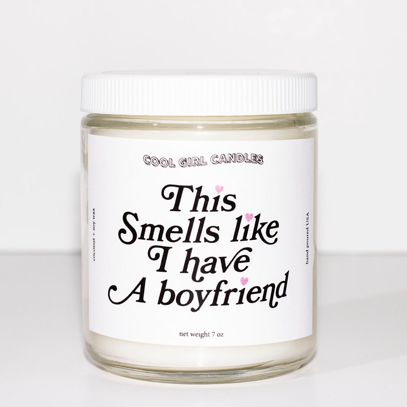 Puede incluir: Un tarro de vela blanco con una tapa blanca. La etiqueta dice "COOL GIRL CANDLES" y "This Smells like I have A boyfriend". La vela pesa 7 oz.