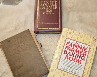 May include: Three cookbooks including a maroon hardcover titled The Original Fannie Farmer 1896 Cook Book, a worn tan Boston Cooking-School Cook Book, and a cream-colored hardcover titled The Fannie Farmer Baking Book by Marion Cunningham.