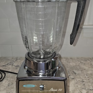 May include: A silver Osterizer Classic VIII blender with a clear glass jar and a black handle. The blender has a variety of settings, including "Pulse", "High", "Low", "Start", and "Off".