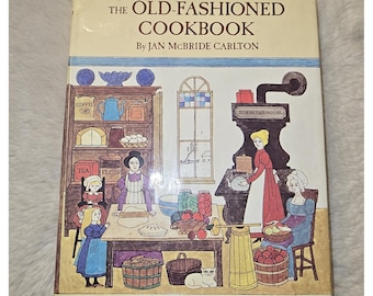 May include: A hardcover book titled The Old-Fashioned Cookbook by Jan McBride Carlton with illustrations by Alice and Martin Provensen. The cover features a colorful drawing of a kitchen scene with people, a stove, a cupboard, and baskets of food.