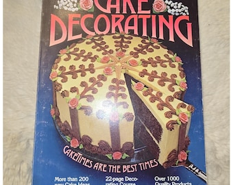 May include: The 1980 Wilton Yearbook of Cake Decorating features a dark blue cover with a large round cake decorated with brown frosting swirls and pink roses. The text reads Cake Decorating, Caketimes Are The Best Times, and other details.