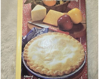 May include: The Illustrated Encyclopedia of American Cooking by Editors of Favorite Recipes Press is a hardcover book featuring a front cover image of a golden-brown baked pie, various cheeses, and fresh apples on a red patterned tablecloth.