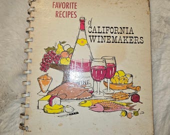 May include: A spiral-bound cookbook titled FAVORITE RECIPES of CALIFORNIA WINEMAKERS. The cover features a colorful illustration of a wine bottle, two glasses of red wine, a roasted turkey, various fruits, vegetables, fish, and cheese.