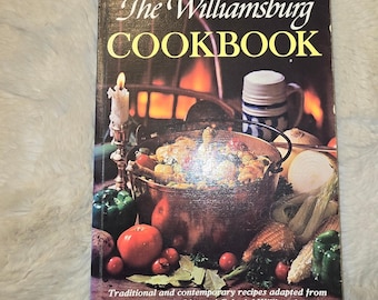 May include: The Williamsburg Cookbook, updated and enlarged, features a cover image of a copper pot filled with food, a lit candle, and a beer mug. The text reads: The Williamsburg Cookbook, Updated and Enlarged, Traditional and contemporary recipes adapted from the taverns and inns of Colonial Williamsburg.