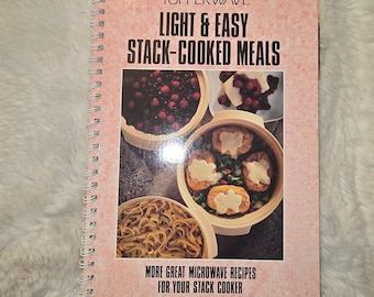 May include: A spiral-bound cookbook titled Tupperwave Light & Easy Stack-Cooked Meals. The pink cover features photographs of food in round containers, including berries, pasta, and cooked patties topped with melted cheese for microwave cooking.