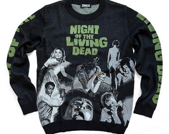May include: Black long-sleeved sweater with a graphic print of the movie "Night of the Living Dead". The sweater has green text and images of zombies.