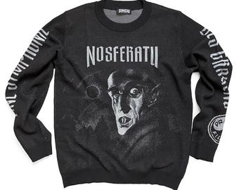May include: Black long-sleeved sweater with a white graphic print of Count Orlok from the 1922 film "Nosferatu", a German expressionist vampire film. The sweater has the text "NOSFERATU" printed on the front.