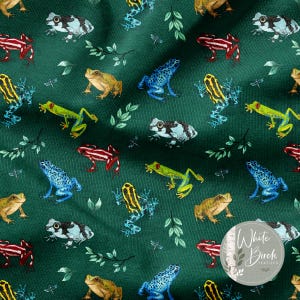 May include: A fabric with a repeating pattern of colorful frogs in various poses. The frogs are in shades of green, blue, yellow, red, and black, set against a dark green background with sprigs of leaves and dragonflies.